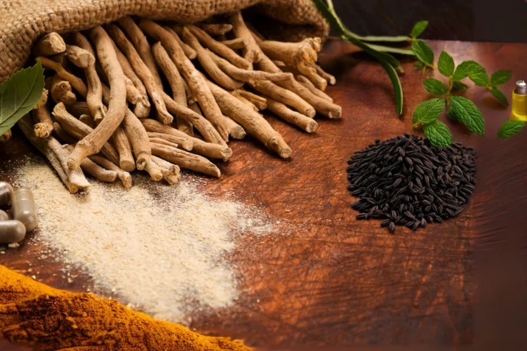 A rustic display of natural thyroid remedies including ashwagandha roots, turmeric powder, black cumin seeds, peppermint leaves, and herbal supplements.